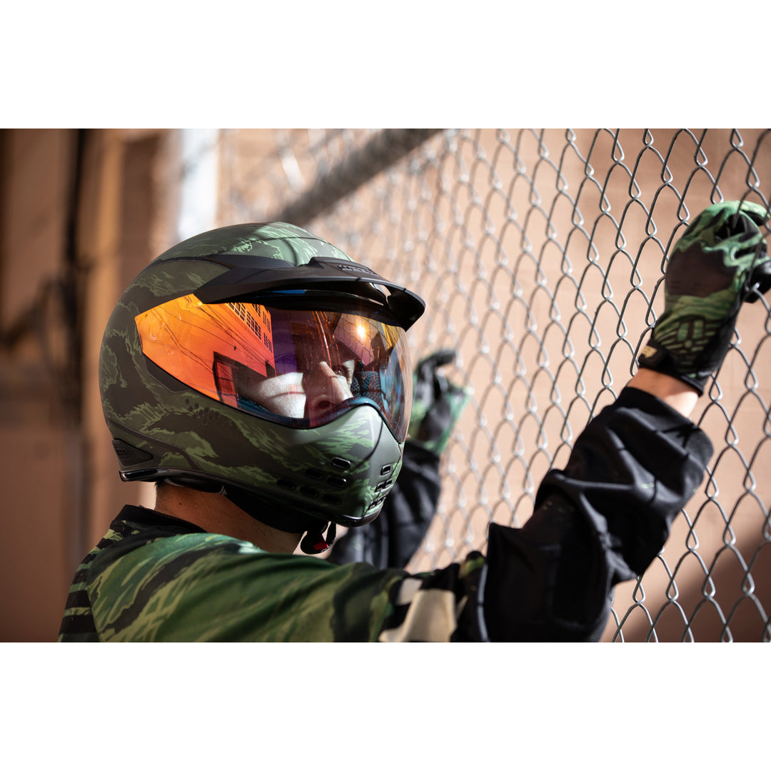 ICON Domain™ Tiger's Blood Helmet Green - Lifestyle of Rider Wearing Helmet while looking through chainlink fence
