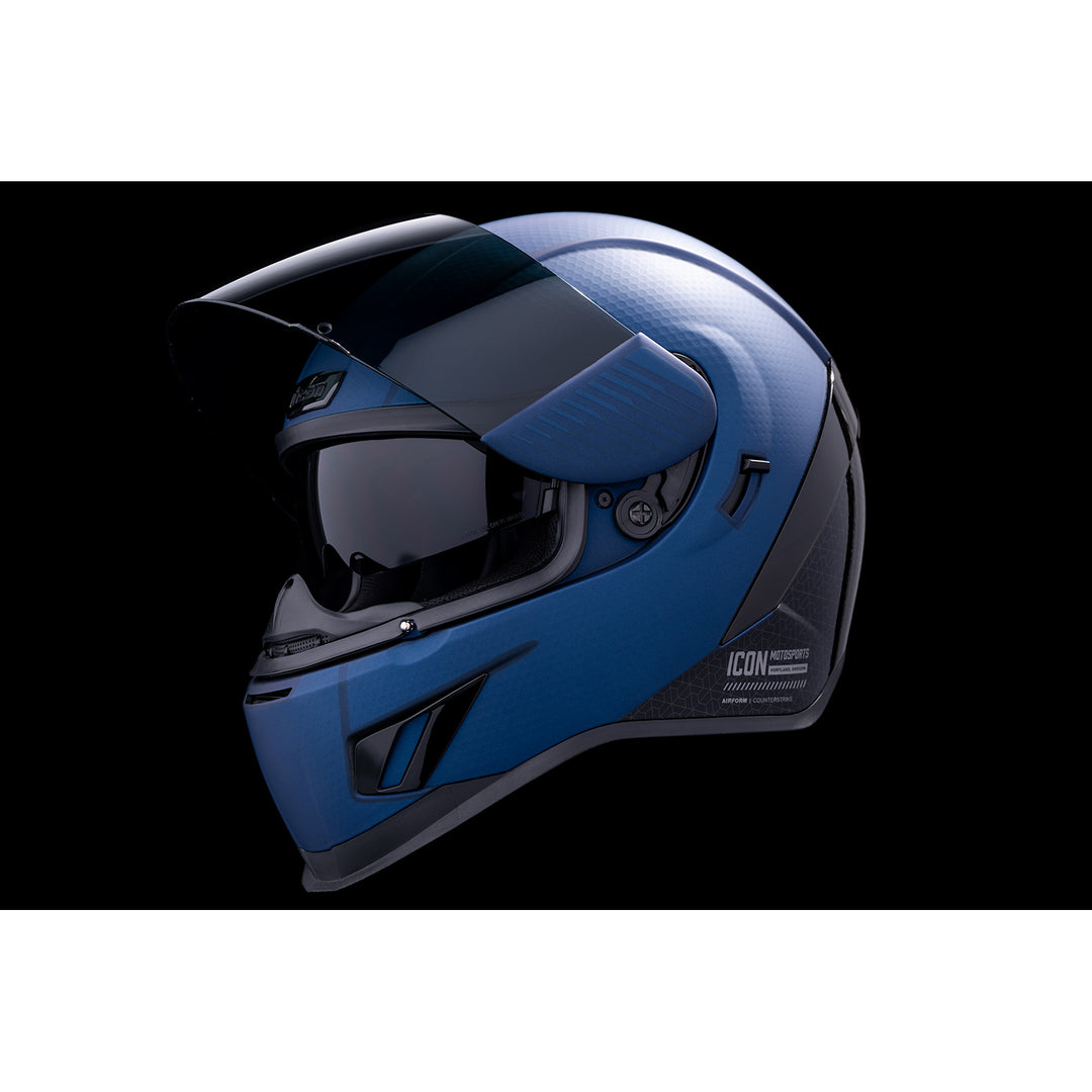 ICON Airform™ Counterstrike MIPS® Helmet Blue - Front Left Side View with Dark Studio Background, Faceshield Raised, and Drop Down Sun Visor Lowered