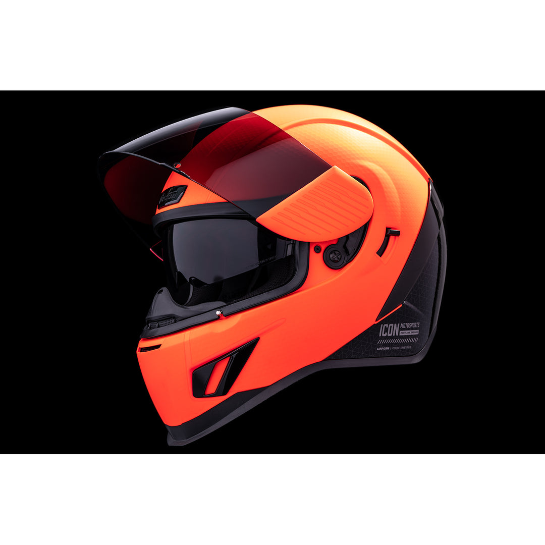 ICON Airform™ Counterstrike MIPS® Helmet Red - Front Left Side View with Dark Studio Background, Faceshield Raised, and Drop Down Sun Visor Lowered