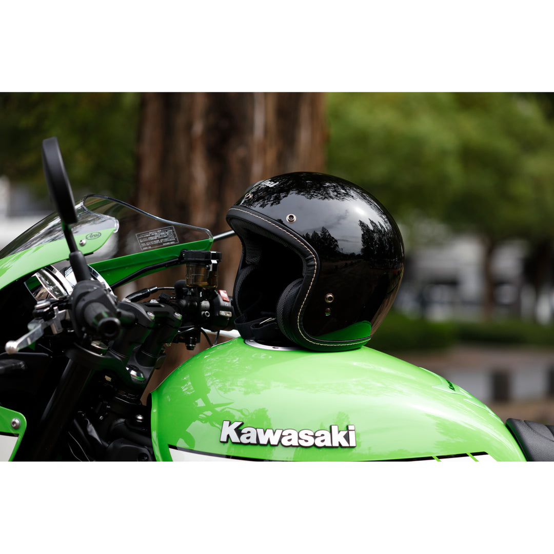 Arai Classic-V Helmet - Lifestyle shot of black helmet resting on tank of green motorcycle