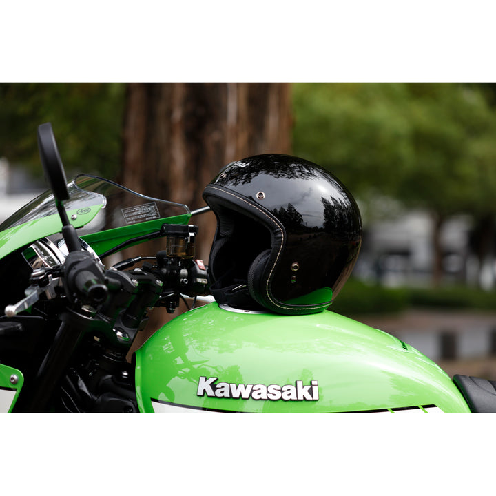 Arai Classic-V Helmet - Lifestyle shot of black helmet resting on tank of green motorcycle