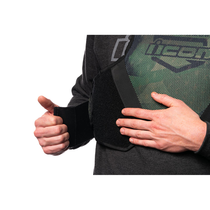 ICON Field Armor Softcore™ Vest Green Camo - Close-Up of Model Adjusting Lower Chest Strap